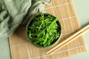 Yeşil ahşap arka planda lezzetli yosun salatası ile kase, yakın plan.