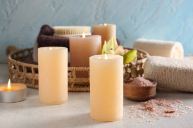 Beyaz grunge arka planında yanan mumlarla güzel bir spa seti, yakın plan.