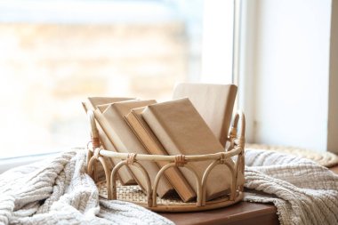 Wicker tray with different books on windowsill in living room, closeup