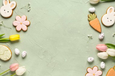 Lezzetli Paskalya kurabiyelerinden yapılmış çerçeve, yeşil grunge arka planda yumurtalar ve çiçekler