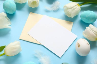 Mavi zemin üzerinde boş kart, lale ve Paskalya yumurtaları olan kompozisyon