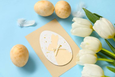 Tebrik kartı, lale ve yumurtalı kompozisyon mavi arka planda. Paskalya kutlaması