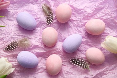 Kırışık kağıda boyanmış Paskalya yumurtaları, tüyler ve lale çiçekleri.
