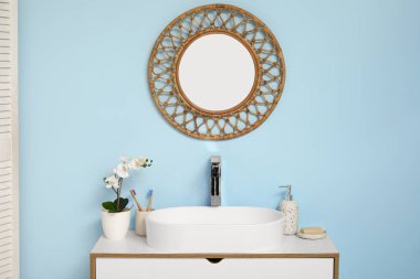 Banyoda mavi duvarın yanında banyo malzemeleri olan modern lavabo.