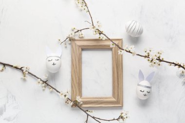 Boş çerçeve, çiçek açan dallar ve beyaz arka planda Paskalya yumurtaları. Üst görünüm