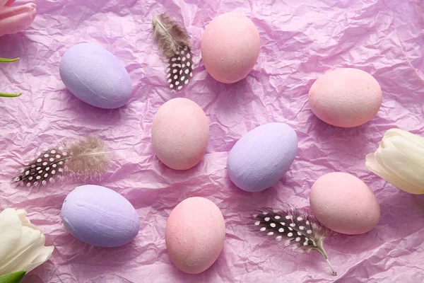 Kırışık kağıda boyanmış Paskalya yumurtaları, tüyler ve lale çiçekleri.