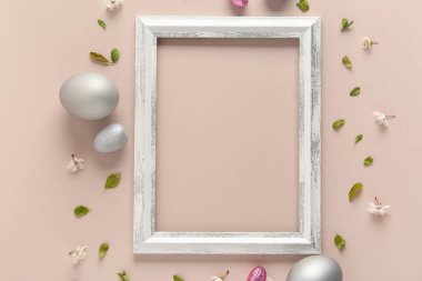 Çerçeveli, çiçekli, yapraklı ve bej arka planda Paskalya yumurtalı güzel kompozisyon