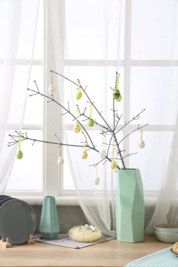 Modern mutfakta ağaç dalları ve paskalya yumurtaları olan bir vazo.