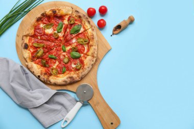 Lezzetli pizzalı kompozisyon, malzemeler ve mavi arka planda kesici.