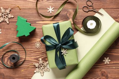 Noel hediyesi kutusu, ambalaj malzemeleri ve kahverengi ahşap arka planda farklı dekorasyonlar.