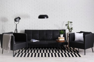 Siyah deri kanepe, sehpa, koltuk ve lambalar oturma odasında.