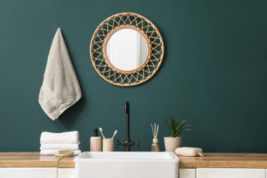 Lavabo ve banyo aksesuarları banyodaki yeşil duvarın yanında.