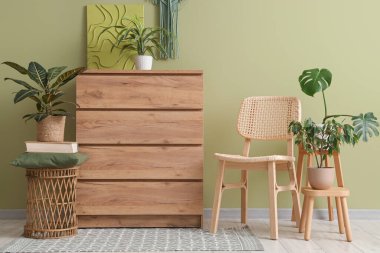 Çekmeceler ve içi yeşil duvarın yanında çiçekli sandalye.