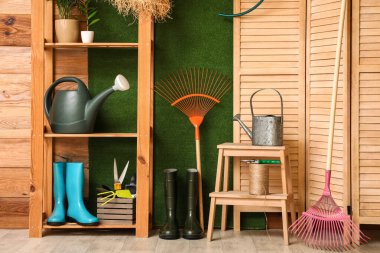 Raflar, perdeler ve bahçe malzemeleri odasındaki ahşap duvarın yanında.