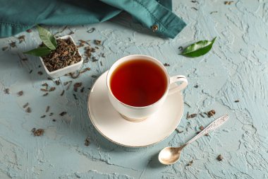 Mavi grunge arka planda bir fincan lezzetli siyah çay ve kuru yapraklar.