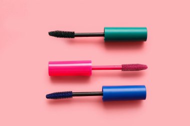 Pembe arka planda farklı rimel fırçaları, yakın plan.
