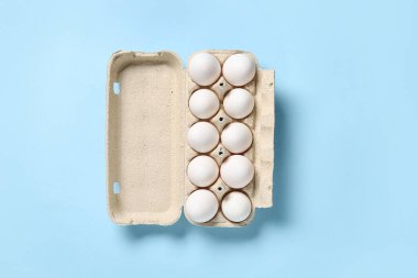 Mavi arka planda taze tavuk yumurtası olan mukavva tutucu.