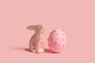 Seramik tavşan ve Paskalya yumurtası renkli arkaplanda incilerle süslenmiş.