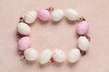 Paskalya yumurtalarından yapılmış bir çerçeve. Bej renginde inciler ve çingene çiçekleriyle süslenmiş.