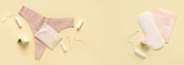 Bej arka planda tampon ve külotlu adet pedleri ve metin için yer var.