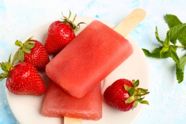 Mavi arka planda tatlı çilekli dondurma tabağı.