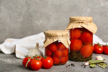 Konserve domatesli kavanozlar ve gri arka planda sarımsak.