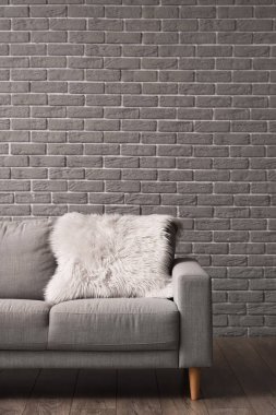 Gri tuğla duvarın yanında kürklü kanepe.