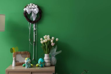 Yeşil duvarın yanındaki klozette lale ve Paskalya dekoru olan vazo.