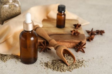 İçinde gerekli yağ şişeleri, anason yıldızları, kurutulmuş tohumlar ve gri grunge masasında kepçe bulunan ahşap tahta tahta.