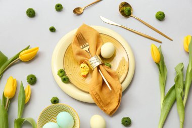 Paskalya kutlaması için gri arkaplanda çiçekler olan şık masa ayarları