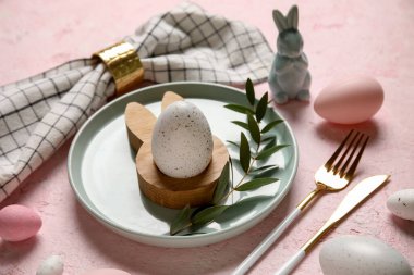 Paskalya yumurtaları, oyuncak tavşan ve pembe arka planda okaliptüs dalıyla güzel bir masa. Yakın plan.