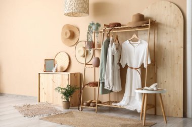 Koridorun iç tarafındaki bej duvarın yanında giysi ve aksesuarlarla dizilin.