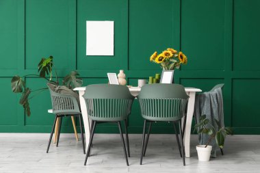 Yemek masası olan bir oda, vazoda ayçiçekleri ve bitkiler.