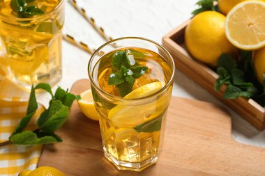 Beyaz arka planda nane ve turunçgil meyveli limonlu buzlu çay, yakın plan.