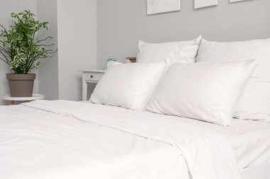 Odasında beyaz çarşaf olan büyük yatak.