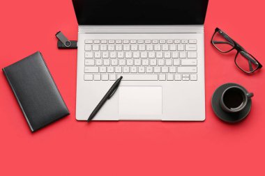 Kırmızı arka planda defter, kalem, kahve, gözlük ve dizüstü bilgisayar.