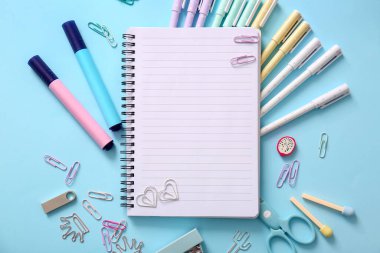 Mavi zemin üzerinde boş defter ve farklı okul sayfası olan kompozisyon