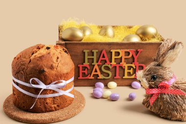 Lezzetli Paskalya pastası, boyalı yumurta ve bej arka planda ahşap kutu.