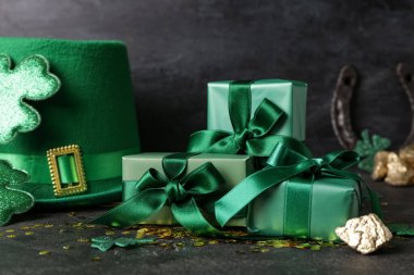 Leprikon şapkalı hediye kutuları, pullar ve siyah grunge arka planda altın. Aziz Patrick Günü