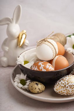 Beyaz arka planda süslü Paskalya yumurtaları, tavşan ve bahar çiçekleri olan tabaklar.