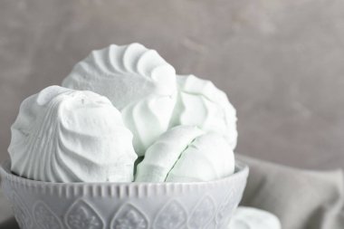 Gri arka planda bir kase tatlı zefir.