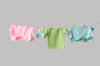 Gri arka planda ipte sallanan farklı temiz kıyafetler.