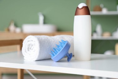 Saç derisi masaj aleti. Banyodaki rafta şampuan ve havlu. Yakın plan.