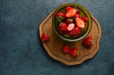 Koyu arkaplanda taze çilekli kase.