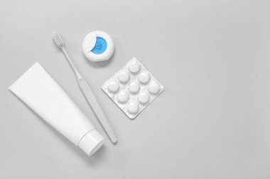 Diş fırçası, diş ipi ve gri arka planda diş eti.