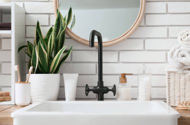 Lavabo ve banyo aksesuarları banyodaki beyaz tuğla duvarın yanında.