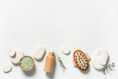 Spa taşlı kompozisyon, gerekli yağ şişesi, masaj fırçası ve hafif arka planda deniz tuzu.