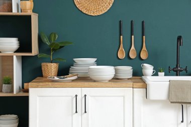 Mutfağın içinde mavi duvarın yanında farklı plakalı tezgahlar var.