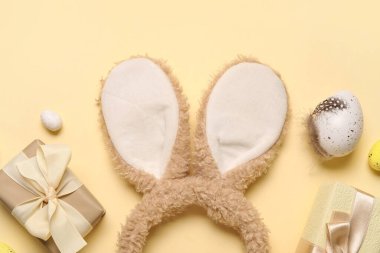 Paskalya yumurtalı tavşan kulakları ve bej arka planda hediye kutuları.