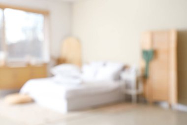 Beyaz battaniyeli rahat yatağın bulanık manzarası ve şık yatak odasında yumuşak yastıklar.